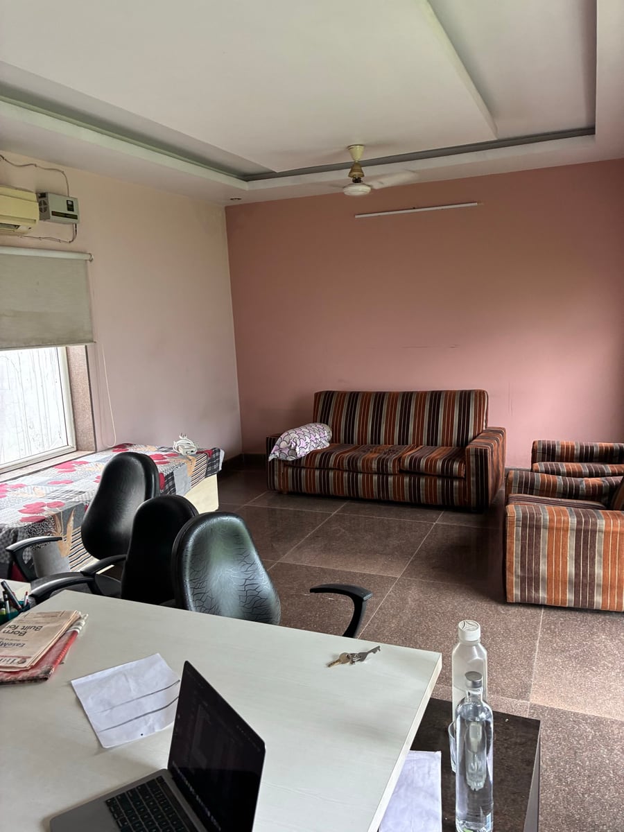 Before: an ordinary Indian living room with pink walls, a ceiling fan, a split AC, a striped sofa set and a working desk in the foreground